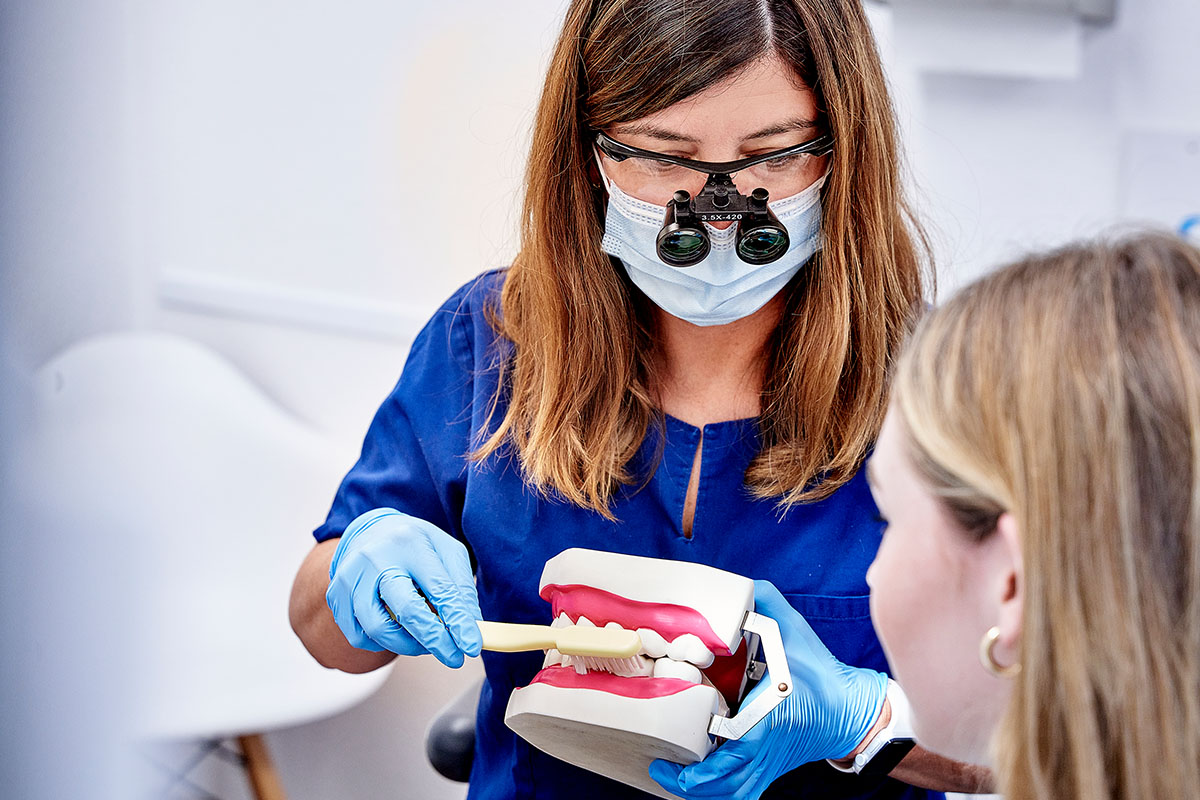 Parodontitisbehandlung in der Zahnarztpraxis Kowadent Hückelhoven: Zahnärztin zeigt das Zähneputzen am übergroßen Zahnmodell